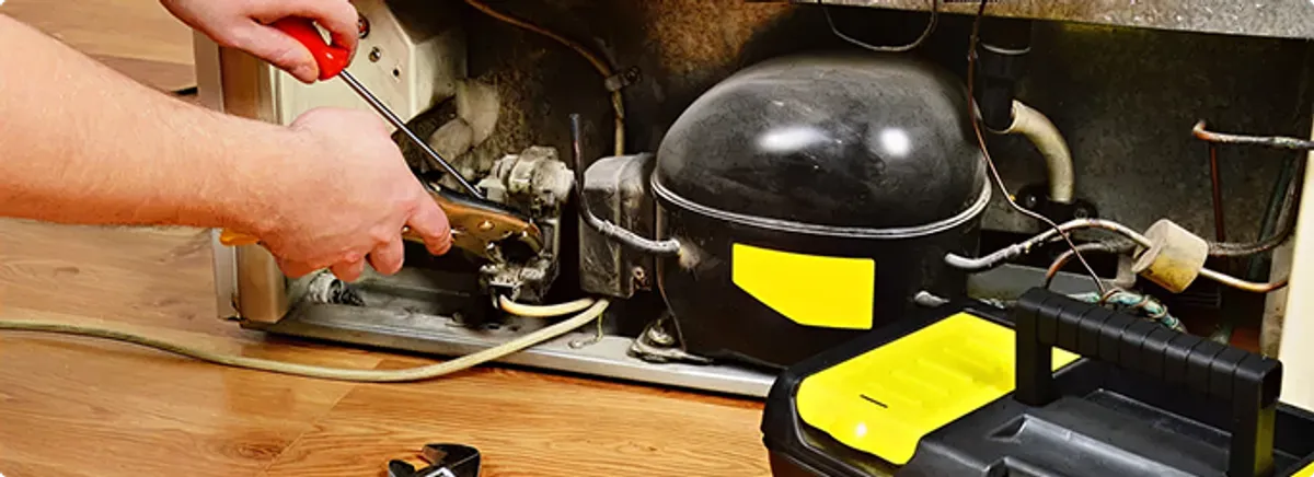 Refrigerator repair technician fixing the compressor and wiring in Galloway, OH
