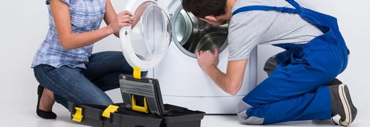 Washer repair technician inspecting a front-load washing machine with tools in Columbus, OH