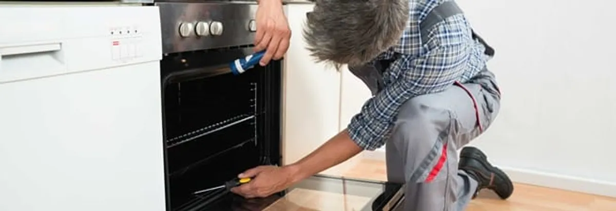 Oven repair technician inspecting and servicing an electric oven in Columbus, OH