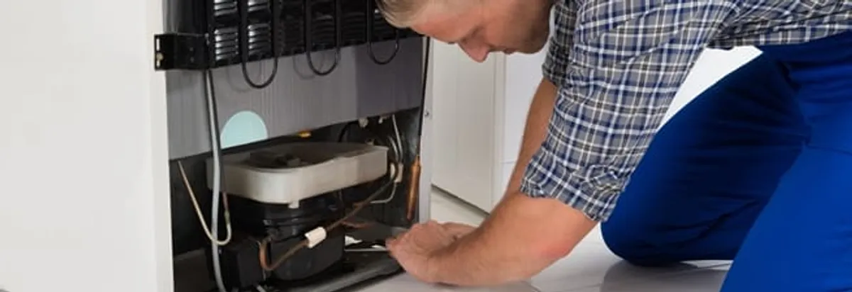 Refrigerator repair technician servicing the compressor and condenser area in Columbus, OH