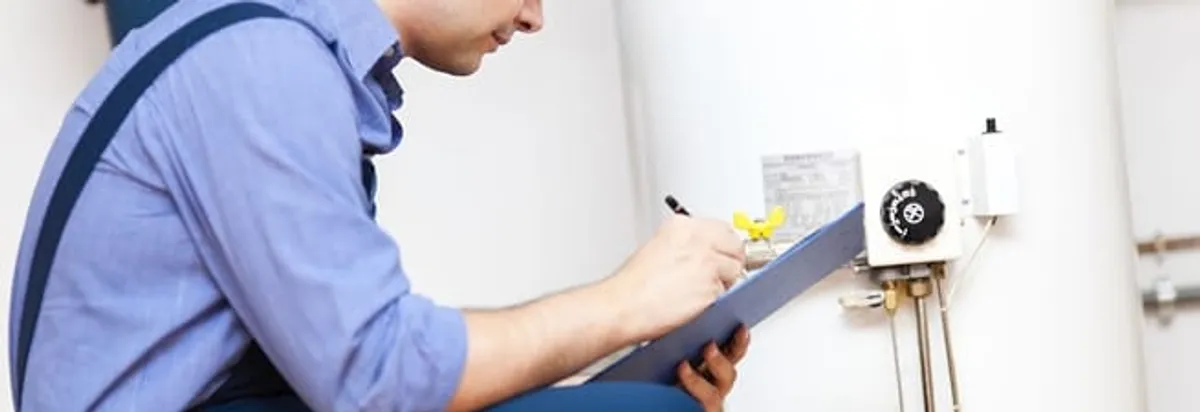 Water heater repair technician inspecting the unit and recording service notes in Columbus, OH